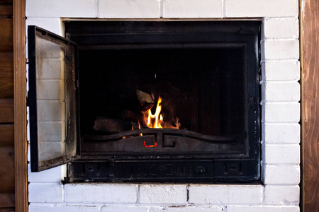 木头在家里舒适的壁炉里燃烧。 壁炉里着火了。 冬季和圣诞节假期的概念。