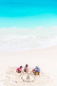父亲和小女儿做沙子城堡在热带海滩
