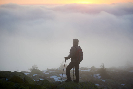 游客徒步旅行者背背包和徒步旅行棒在岩石山峰上，欣赏山谷全景