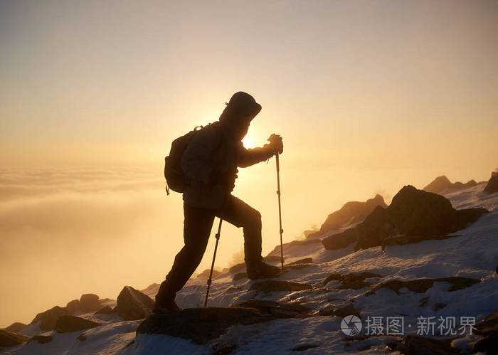 游客徒步旅行者背着背包和登山杖在落基山山顶上日落背景的后景