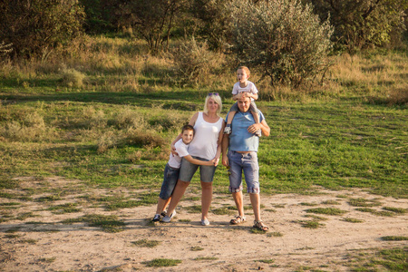一个幸福的四口之家，穿着白色T恤和蓝色牛仔短裤在大自然中休息和玩耍。