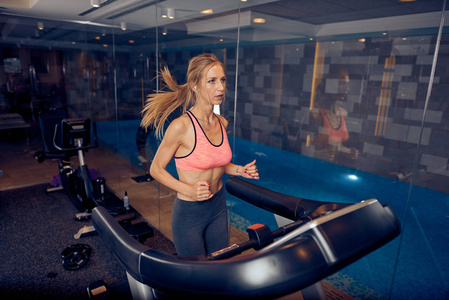 女人在跑步机上跑步。 健身房内部健康生活方式理念。