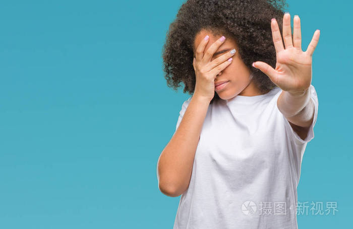 年轻的美国黑人妇女在孤立的背景上用手遮住眼睛用悲伤和恐惧的表情做