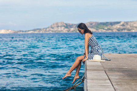 暑假概念。 意大利撒丁岛码头放松的美女