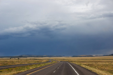 蓝山前草原之间的沙漠公路。 夏日黑天，天空中乌云密布
