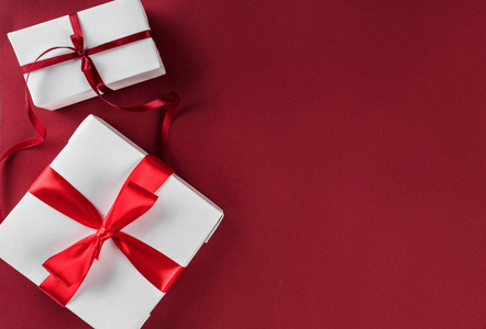 圣诞礼品盒，红色纸背景上有红色丝带。 圣诞节和新年快乐主题。 平躺顶部视图空间文本