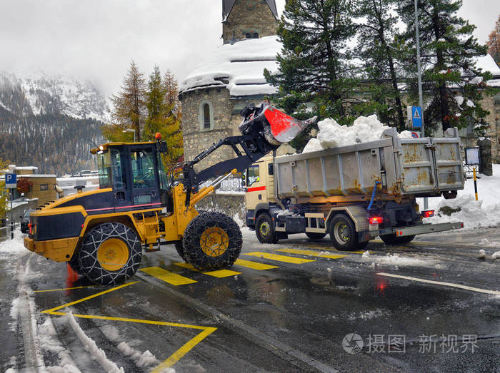 清雪拖拉机清雪机在自卸车上装载一堆雪.