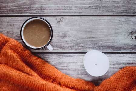 冬天舒适的概念。 木桌上放着橙色针织毛衣蜡烛和牛奶咖啡