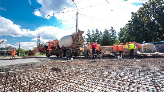 混凝土工程的道路建设与许多工人和搅拌机时间推移超移。 将砂浆浇注到金属钢筋上。 重建电车轨道