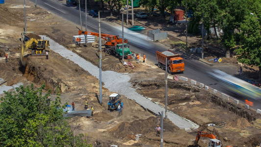 工业卡车装载机挖掘机和推土机在道路施工现场移动土方并装载到翻斗车中。 重建电车轨道的鸟瞰图