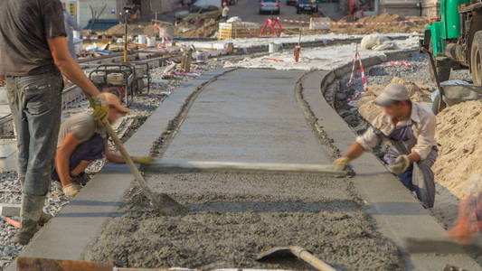 混凝土工程的道路建设，许多工人在统一和搅拌机时间推移。 重建电车轨道