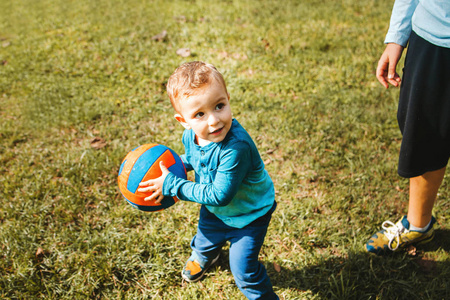 快乐的小男孩在公园里玩球，肖像画