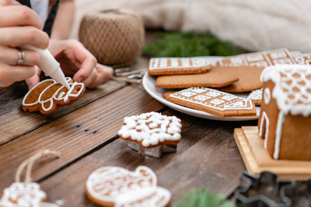 一个年轻的女孩装饰姜饼干的形式雪人圣诞节早晨。女人在蜂蜜姜饼上画冰。木棕色的桌子。复制空间