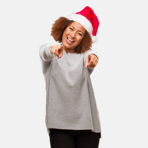 年轻的黑人妇女戴着圣诞帽，兴高采烈，面带微笑