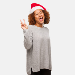 年轻的黑人妇女戴着圣诞帽做着胜利的姿态