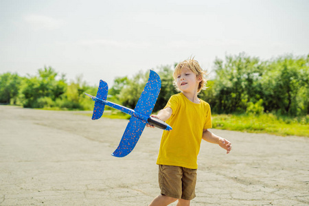 快乐的孩子在旧跑道背景下玩玩具飞机。 和孩子们一起旅行的概念。