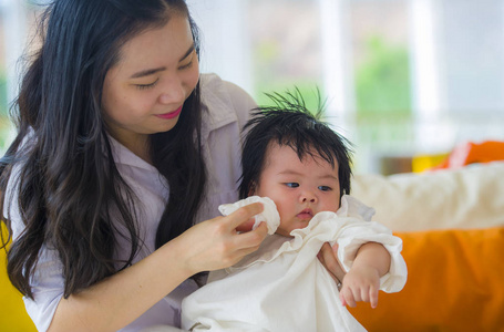 生活方式坦率的肖像年轻，快乐和可爱的亚洲韩国妇女玩和抱着甜蜜的表达能力的女婴坐在度假胜地的母亲和小女儿爱的概念