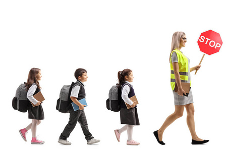 全长轮廓照片学童走在一名女教师后面，穿着安全背心和白色背景上隔离的停车标志