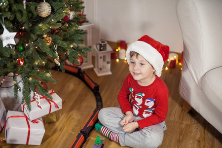 圣诞树附近一个戴着圣诞老人帽子的快乐4岁男孩的肖像。 圣诞节。 假日。 新年。 幸福。 孩子。 很舒服。