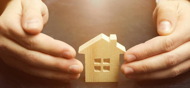 保险代理人以保护的姿态保护房子。财产保险保障和住房的概念..家的安全保障..人寿保险和家庭。房地产