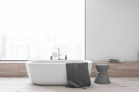 现代浴室的内部有白色墙壁，木制地板，带有城市景观的全景窗户，白色浴缸和灰色椅子。3D渲染