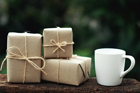 简单的环保礼品盒包装与棕色纸在老式木桌上，绿色，现在的概念复制