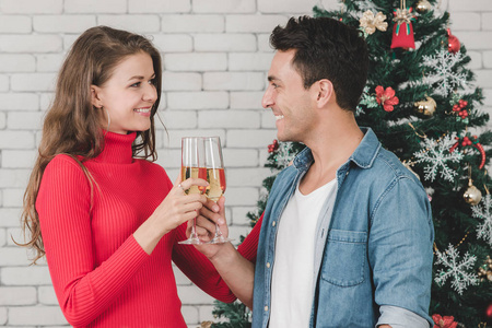 高加索夫妇正在庆祝他们的圣诞节，一起喝白葡萄酒，他们的爱在这个圣诞节和圣诞树装饰品。