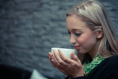 在咖啡店喝热咖啡的年轻女子