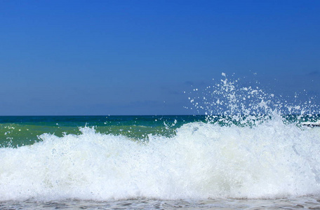 海浪拍打在鹅卵石海岸，使飞溅的水和蓬松的白色泡沫泡。