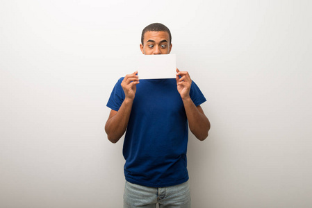 年轻的非裔美国男人在白色的墙上拿着一个标语牌插入一个概念