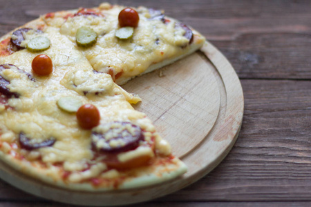 自制的热比萨饼，配上意大利香肠奶酪泡菜和西红柿，在木制背景下准备吃