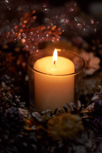 来临装饰花环蜡烛。 在黑暗中，一支蜡烛在一个美丽的装饰花环上燃烧。