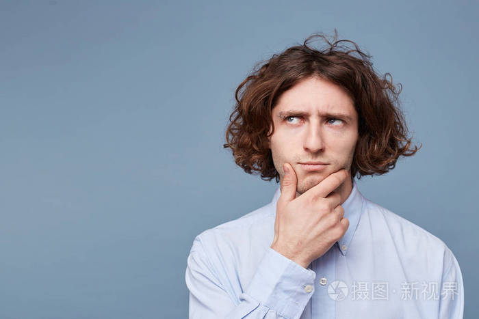 照片 自信的,沉思的,英俊的年轻人怀疑触摸的脸,而思考的是,穿着白色