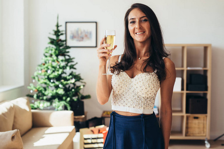 新的一年。拿着一杯香槟酒的年轻女子。庆祝和微笑。圣诞节