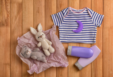 木制背景的婴儿衣服玩具和化妆品