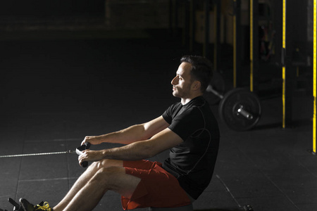 一个年轻的运动员在健身房做俯卧撑运动。 黑暗摄影概念与复制空间文本区域。