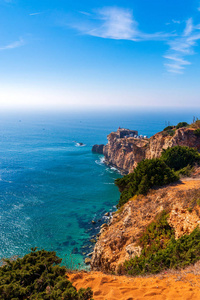葡萄牙纳扎雷海边的古堡。 岩石悬崖上的灯塔。 大西洋海岸海岸线。 海角斜坡覆盖着绿色植被。 海浪拍打在岩石上。