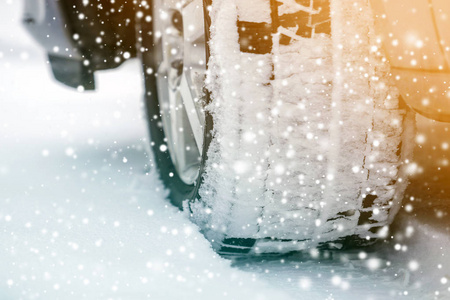 在冬季白雪覆盖的道路上，用新的黑色橡胶轮胎保护器关闭详细的汽车车轮。运输和安全理念..