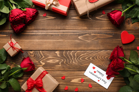 美丽的框架，用红色玫瑰和礼物在木桌上。情人节庆祝活动