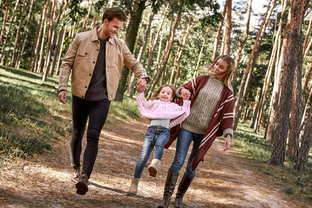 秋天森林里带着小女儿的年轻父母