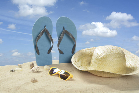 沙滩上挂着带草帽和太阳镜的拖鞋