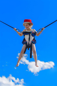 孩子们在蹦床上跳，用橡胶绳在蓝天上。 冒险和极限运动。 夏季娱乐跳跃的概念。