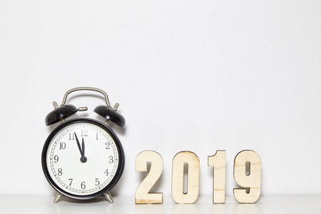 新年快乐概念与闹钟和木制号码2019在白色墙壁背景复制空间。