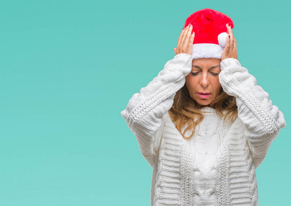 中年老年西班牙裔妇女戴着圣诞帽，在孤立的背景下患有头痛，绝望和压力，因为疼痛和偏头痛。 手放在头上。