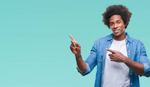 美国黑人男子在孤立的背景上微笑，看着相机，用两只手和手指指向一边。