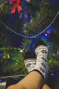 s legs in socks on the background of the Christmas tree