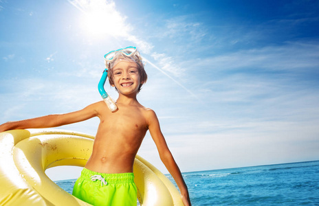 戴水肺面罩和大泳圈对抗热带海景的快乐男孩肖像。