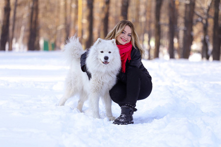 在雪地上冬天的森林里，带着一条狗的美丽的年轻女孩
