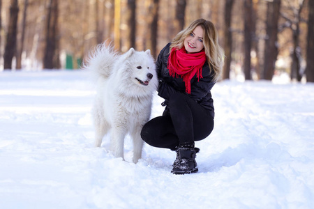 在雪地上冬天的森林里，带着一条狗的美丽的年轻女孩