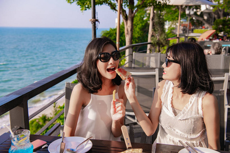 休闲概念。 美丽的女孩正在海边餐馆吃饭。 美丽的女孩正在享受桌子上的食物。